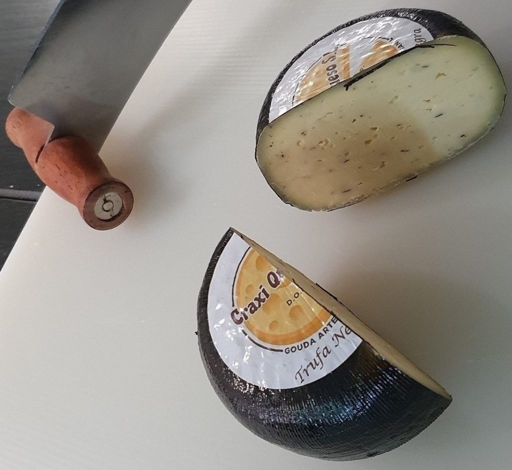 Wheel of Craxi Gouda truffle cheese made from raw cow’s milk, showcasing creamy artisanal Gouda infused with rich black truffle pieces.